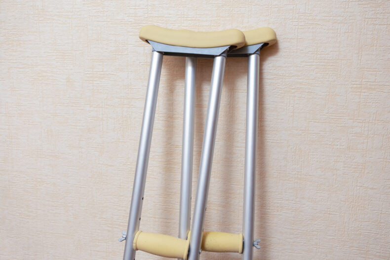 Medical Concepts. Pair of Crutches for Disabled People Placed Against Wall Indoors.Horizontal Orientation