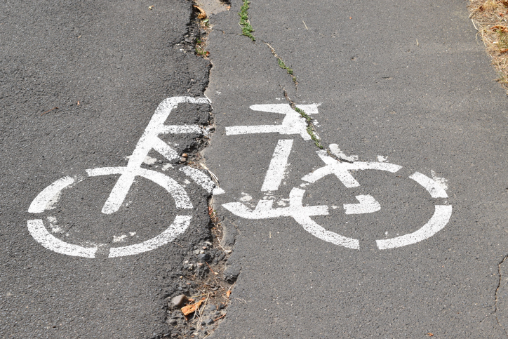 cracked road with a bike lane symbol pained on the surface 